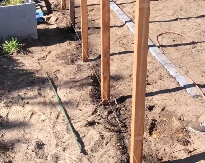 Azobe houten palen worden nauwkeurig langs een gespannen lijn in de grond geplaatst