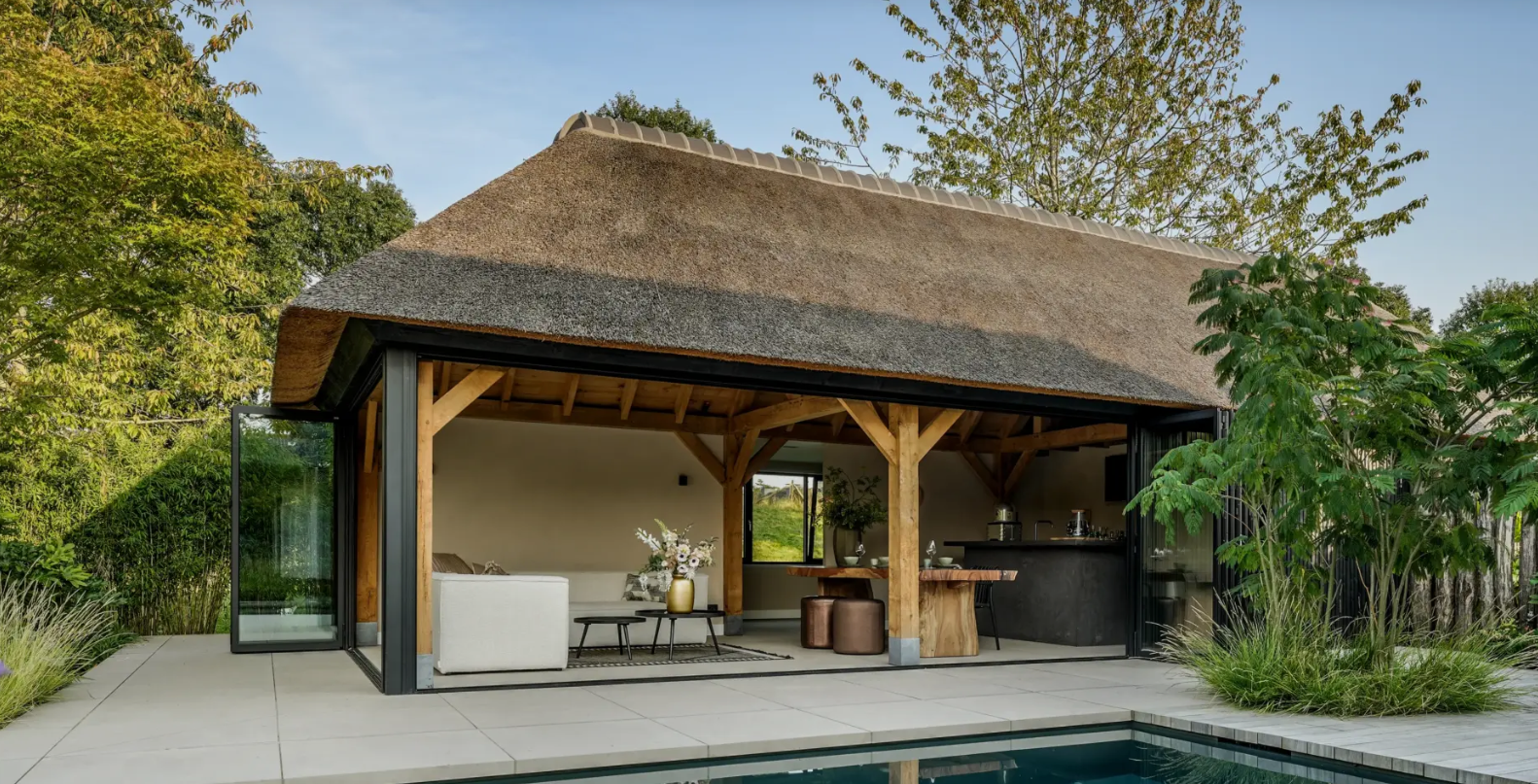 View of the oak pool house with thatched roof next to the pool