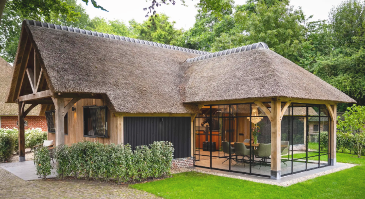 Luxe eikenhouten poolhouse voorzien van zwarte stalen deuren met royale glaspanelen