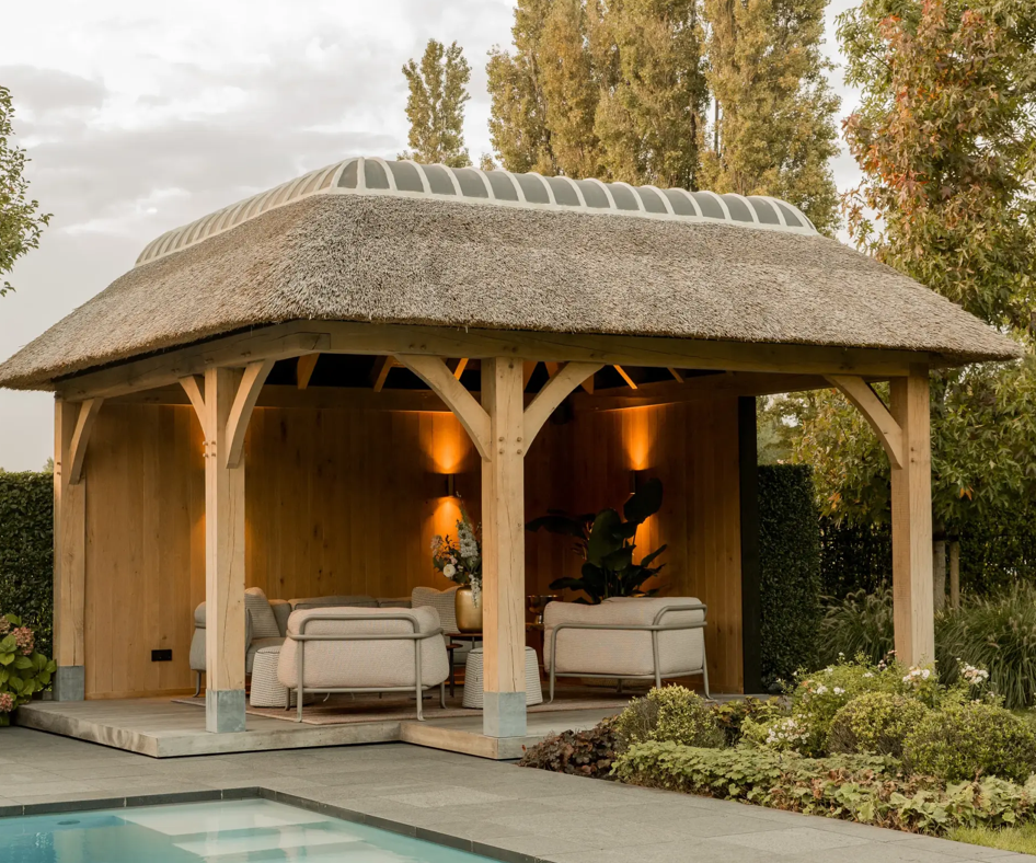Luxe eiken tuinhuis met een laag puntdak en rieten dakbedekking naast een zwembad