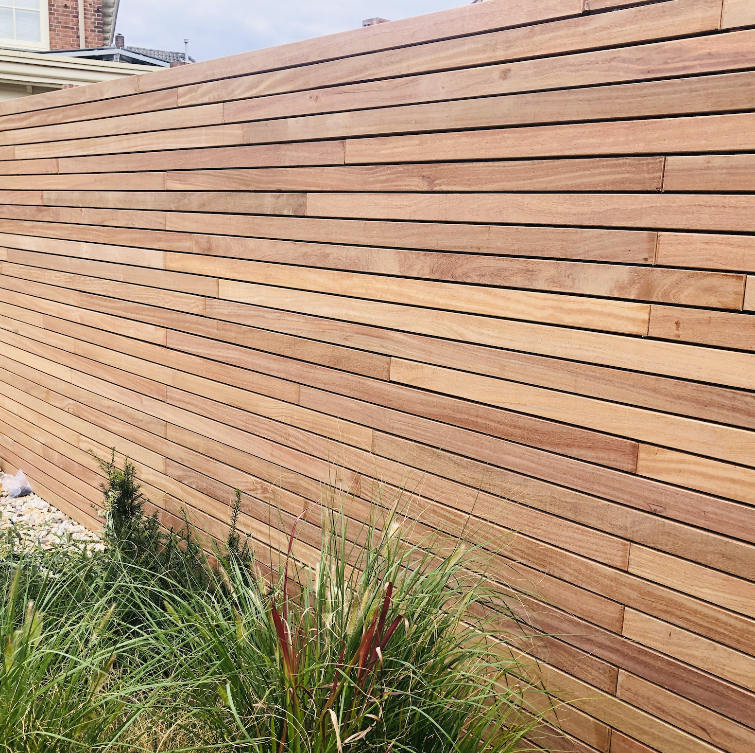 Exclusieve zwarte schutting met Ip&eacute; hardhouten lamellen voor een modern 3D-contrast in de tuin