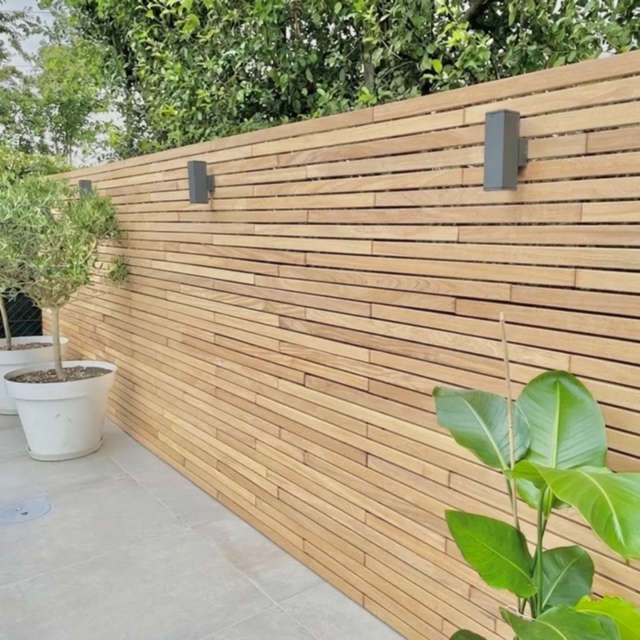 Moderne teak schutting van 5 cm lamellen met wandlampen