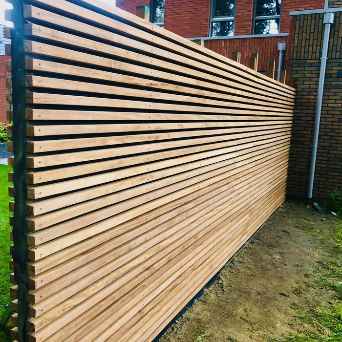 Ipe schutting met smalle horizontale latten Ipe schutting met horizontale smalle latten geplaatst langs een stenen woning