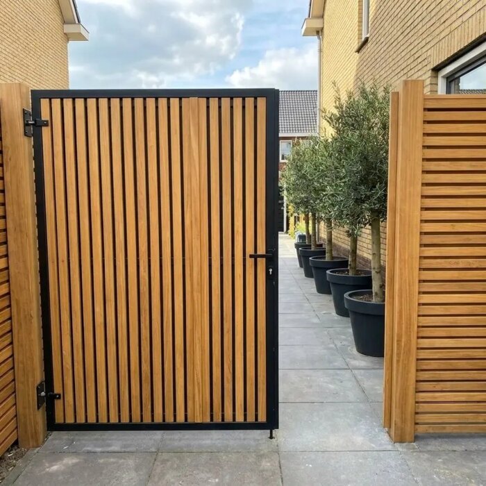 Teak poort op maat met lamellen van 7 cm in een smal zijpad Teak poort op maat met lamellen van 7 cm in een smal zijpad