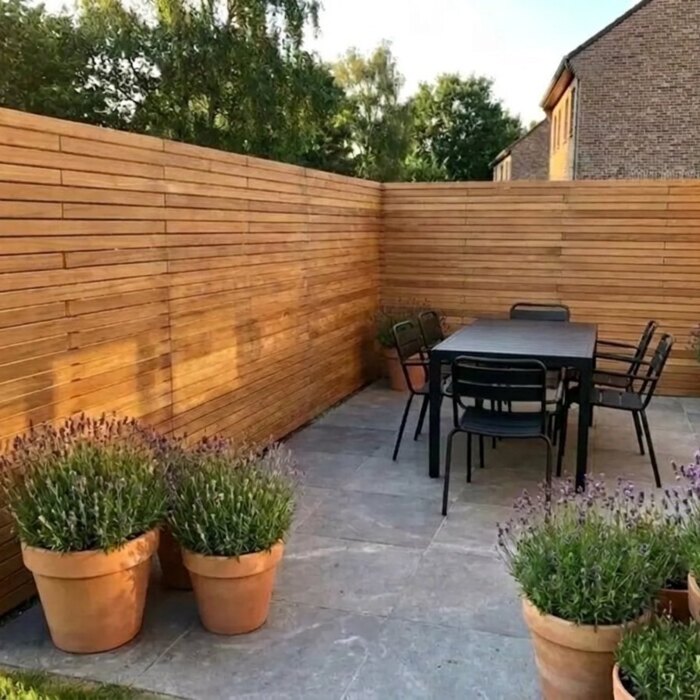 Teak schutting op maat met lamellen van 7 cm, om de hoek van een terras doorgezet Teak schutting op maat met lamellen van 7 cm, om de hoek van een terras doorgezet