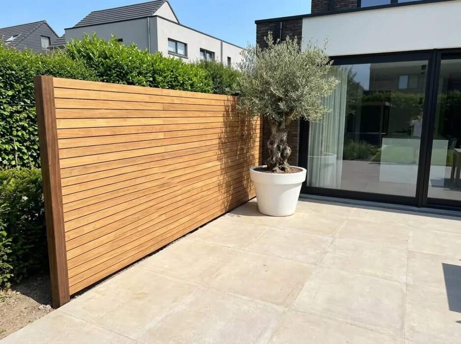 Teak schutting met lamellen van 7 cm in een nieuwbouwtuin met olijfboom