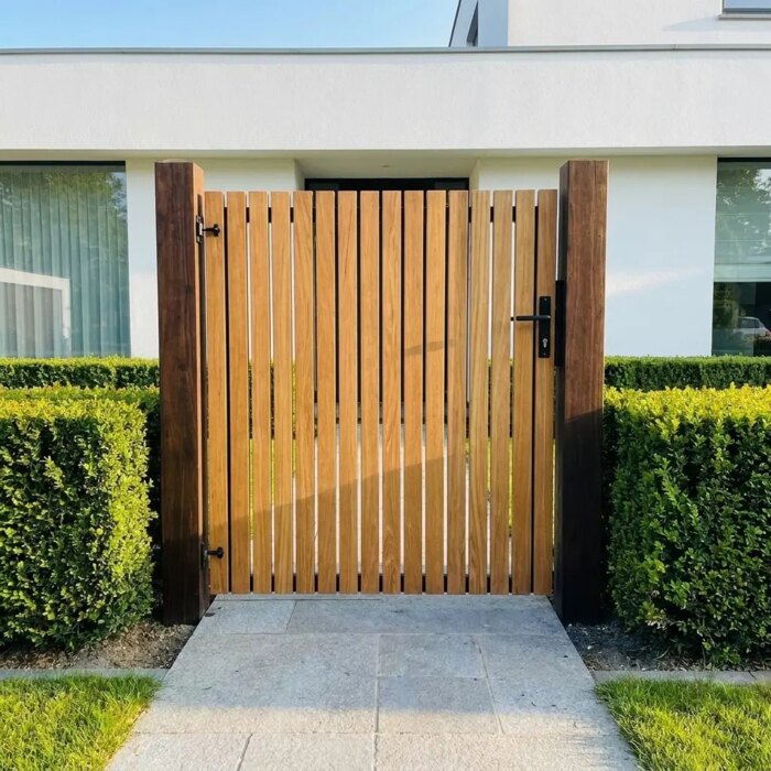 Teak tuinpoort met lamellen van 7 cm in de voortuin van een modern wit huis