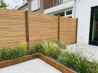 Teak schutting met lamellen van 5 cm in een achtertuin met cortenstalen plantenbak