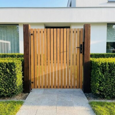 Teak tuinpoort met lamellen van 7 cm in de voortuin van een modern wit huis