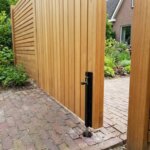 Detail van de zwarte grondgrendel van het vaste deel van de dubbele teak poort