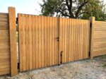 Dubbele teak tuinpoort bij een landelijk huis met grindpad en oude perenboom