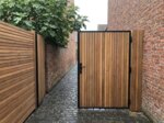 Ipe poort op maat tussen bakstenen muren in een stadstuin