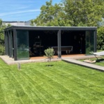 Modern tuinhuis met glazen deuren en vlonder