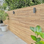 Moderne teak schutting van 5 cm lamellen met wandlampen