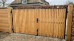 Teak dubbele poort op maat bij een landelijk huis, lamellen van 7 cm