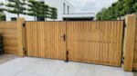 Teak dubbele poort op maat bij een moderne villa, lamellen van 5 cm