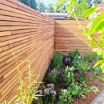 Teak schutting van 5 cm lamellen in een hoek van de tuin met border