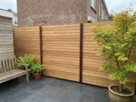 Teak schutting met 9 cm lamellen in een stadstuin met Japanse esdoorn