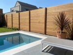 Teak schutting van 9 cm lamellen naast een zwembad in een moderne tuin