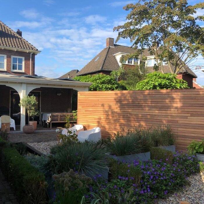 Sfeervolle en strakke Ipé houten lamellenschutting in een compacte stadstuin voor optimale privacy en een luxe uitstraling