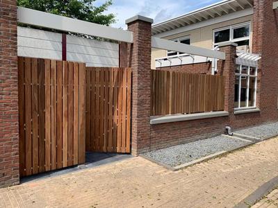Dubbele hardhouten Ip&eacute; poort tussen gemetselde poeren met zijschermen voor moderne stadsvilla